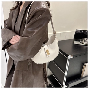 White leather crescent underarm bag with gold metal buckle shown in an office setting