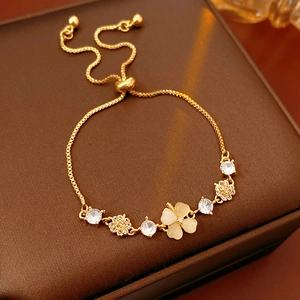 Macro detail of gold-plated clover bracelet with cat eye stone and cubic zirconia inlay