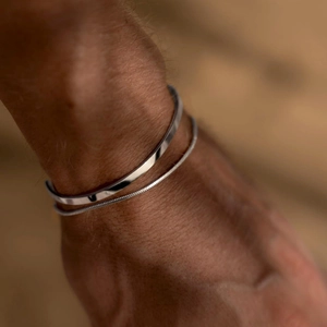 Close-up of minimalist double-layer men's snake and cuban link metal chain bracelets