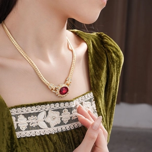 Close-up of vintage snake chain necklace with red gemstone and crystals on model