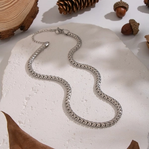 Gros plan d'un collier chaîne serpent argenté sur pierre avec décor automnal