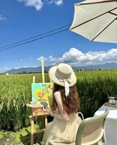 Detail of wide brim straw hat with white ribbon bow decoration in a countryside setting