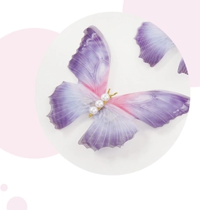 Detail of ethereal tulle butterfly hair clip with gradient purple wings and pearl body