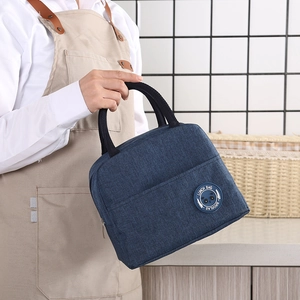 Navy blue insulated lunch bag with panda logo held by a model in a kitchen setting