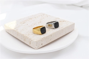 Close-up of gold and silver signet rings with black rectangular stones on stone display