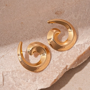 Detailed view of golden spiral swirl earrings with polished metal finish on stone surface