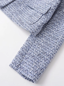 Close-up of premium blue and white tweed fabric texture and pocket stitching detail