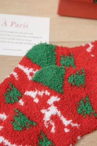 Close-up of thick coral fleece Christmas socks with festive tree patterns and holiday gift box