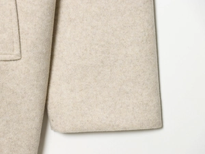 Macro shot of off-white wool fabric texture on the cuff of a French style faux fur coat