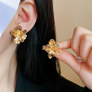 Detailed view of vintage golden flower earrings with irregular hammered texture petals