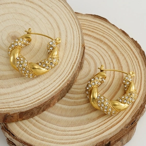 Twisted 18k gold plated stainless steel hoop earrings with sparkling rhinestones on wood