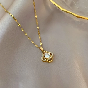 Macro shot of gold clover pendant with sparkling crystals on champagne silk background