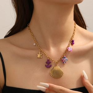 Detail einer Goldkette mit Anhängern wie Muschel, Seeschildkröte und lila Anker am Model