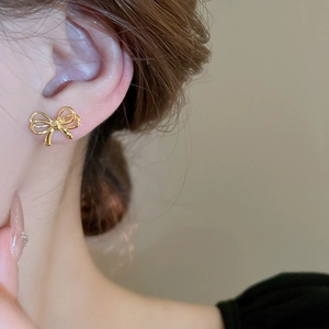 Close-up of elegant gold bow earrings worn by a model showcasing metallic texture