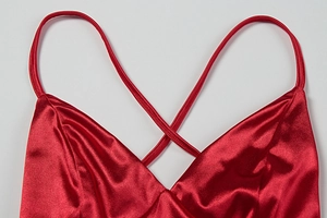 Detail of red satin dress featuring a V-neckline and elegant crisscross spaghetti straps