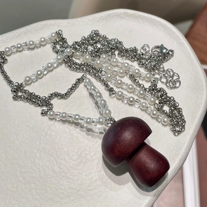 Détail du pendentif champignon en bois avec perles blanches sur collier chaîne argentée