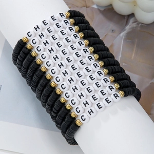 Close-up of stacked CHEER letter bead bracelets with black clay discs and gold accents