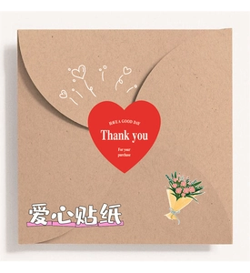 Close-up of red heart-shaped thank you stickers on a brown kraft envelope for gift sealing