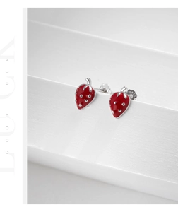 Detailed view of red strawberry earrings in S925 silver on a white geometric stand