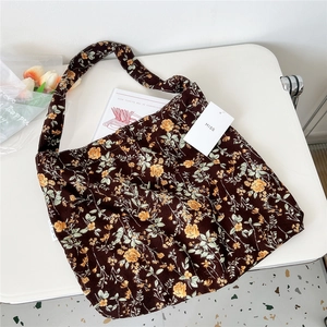 Detail showing vintage floral corduroy shoulder bag with MISS tag on a white table