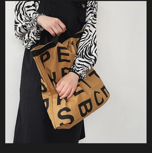 Close-up of khaki canvas tote bag featuring large black letters and durable fabric texture