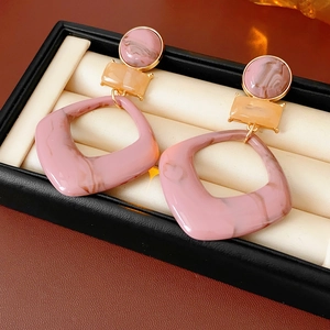 Detail of resin geometric earrings with pink and orange marble pattern on jewelry box