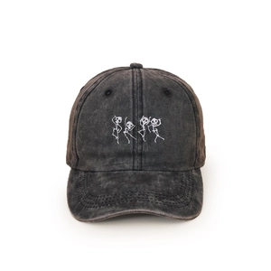 Close-up detail of white skull embroidery on washed charcoal grey baseball cap fabric