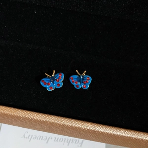 Vintage blue butterfly stud earrings with red crystals on a black velvet jewelry box