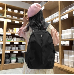 Detail of minimalist black backpack with woven rope zipper and drawstring side pocket