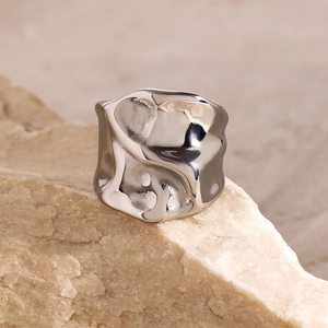 Close-up of irregular hammered silver ring texture on a warm stone background