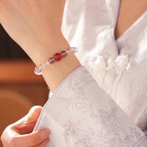 Detailed view of amethyst and agate bead bracelet with Fu character charm on female wrist