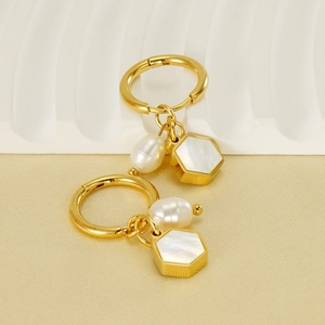 Close-up of 18K gold stainless steel earrings with freshwater pearl and hexagon shell pendants