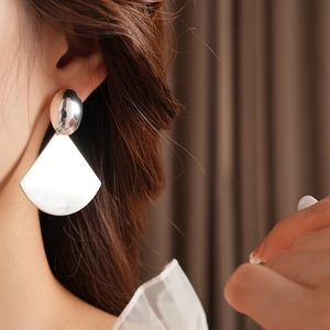 Detail of minimalist brushed metal fan earrings on model with oval stud accent