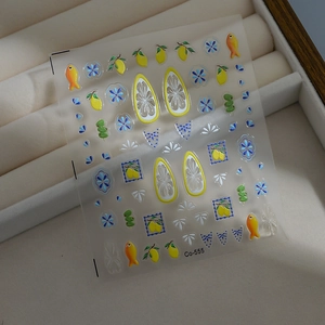 Macro shot of 3D embossed lemon and blue flower nail art stickers on a velvet box