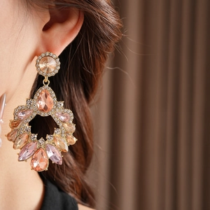 Détail d'une boucle d'oreille goutte en or avec cristaux roses et ambrés sur modèle