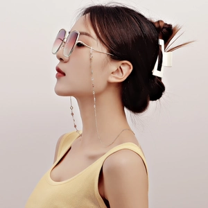 Golden eyewear chain with metal flowers and beads worn by a model in a lifestyle scene