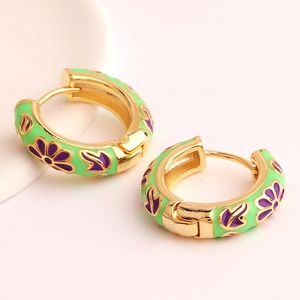 Detailed view of green enamel hoop earrings with purple flower patterns on gold metal