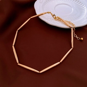 Close-up of golden vintage-style bamboo joint necklace on dark silk fabric