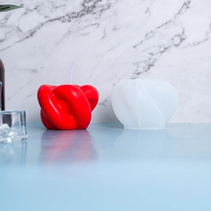 Moule en silicone présentant une bougie en nœud rouge à côté de son moule translucide