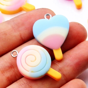 Rainbow resin ice cream and swirl lollipop pendants with metal rings on fingers