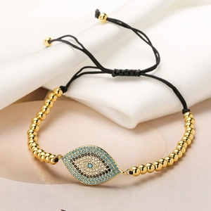 Gold-plated Evil Eye beaded bracelet with adjustable black cord on white silk background