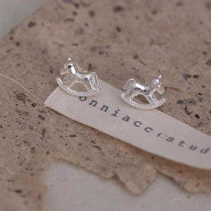 Macro view of silver rocking horse stud earrings with unique hammered metal texture