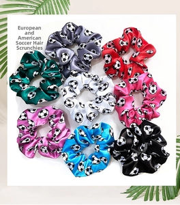 Detail of eight multicolored satin hair scrunchies with classic soccer ball print patterns