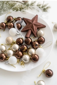 Close-up of champagne and brown Christmas balls and star tree topper in a white plate