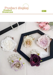 Detail view of colorful silk flower hair ties with large pearls on white fabric