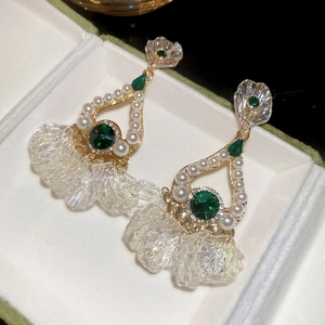 Detailed close-up of vintage earrings with green crystals, pearls and petal tassels