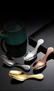 Detail of four stainless steel spoons with crown handles in gold, rose gold, silver and black