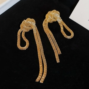 Macro detail of golden woven mesh tassels and knotted design on vintage style earrings