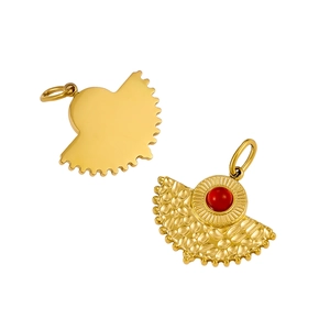 Détail macro du pendentif en forme d'éventail en acier doré avec un insert en pierre rouge