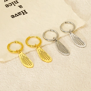 Minimalist stainless steel hollow wing earrings in gold and silver finish shown on props